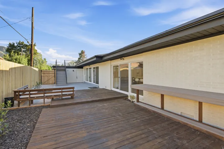 Expansive wood deck with a built-in bench and integrated bar-height counter, featuring a multi-level layout and a privacy fence