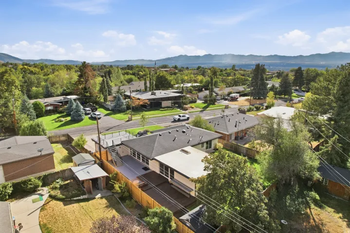 Single-story residence featuring a flat roofline, an expansive exterior deck, and a fenced backyard