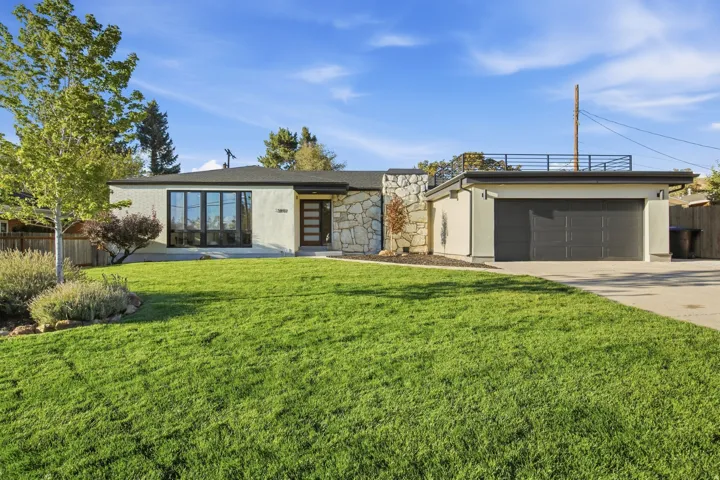 Stucco exterior with stone accents, a multi-pane window, and a dark garage door