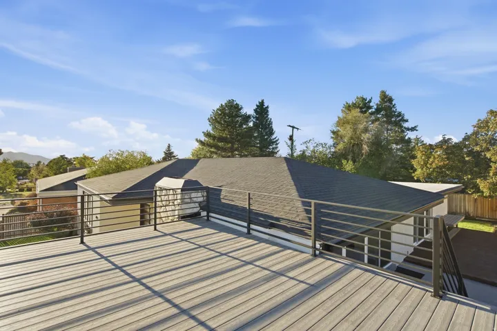 Expansive rooftop deck featuring composite decking, black metal railings, and a partial mountain backdrop