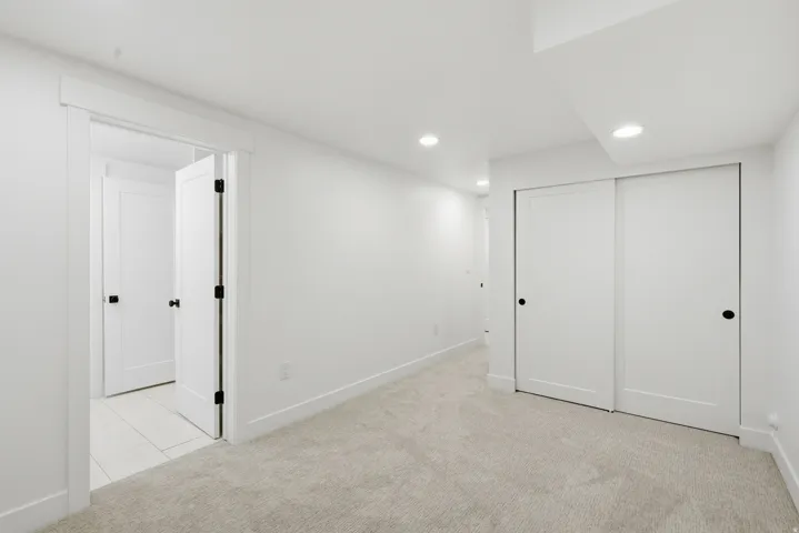 Recessed lighting, light-toned carpeting, white walls, white trim, and a white sliding closet door