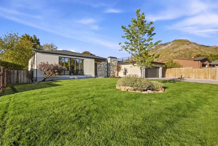 Single-story residence featuring a stone accent façade, expansive front lawn, large windows, and an attached garage