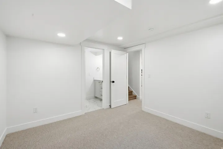 Carpeted flooring, recessed lighting, white walls, white trim, and a white interior door with black hardware
