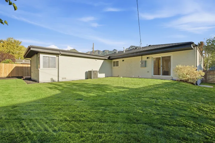 Expansive lawn area with a new wooden fence, brick exterior, and dark trim