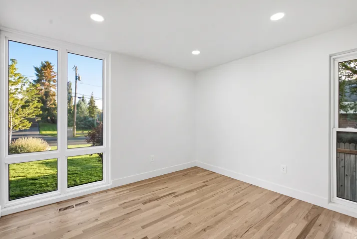 Hardwood flooring, recessed ceiling lighting, and white walls