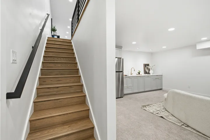 Wood-finish staircase with a black metal handrail
