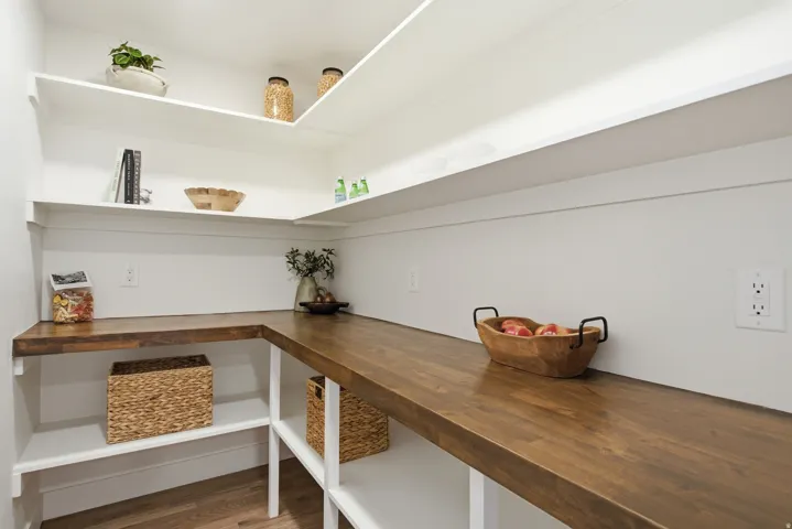 Built-in pantry shelving with white floating shelves and wood-finish countertops