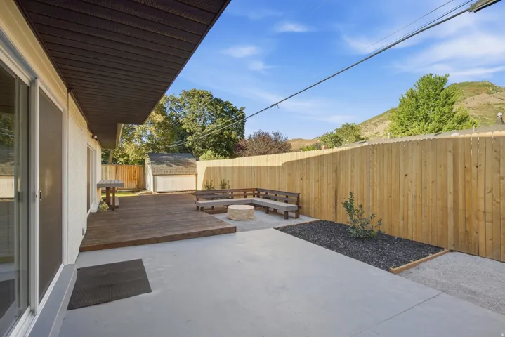 Expansive backyard featuring a wood deck, concrete patio, built-in seating, and a privacy fence