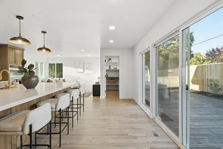 Kitchen island with light-toned countertop, wood-finish flooring, recessed lighting, and sliding glass doors to outdoor decking