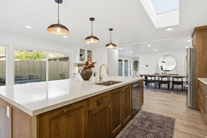Kitchen island with a light-toned countertop, integrated sink, and dishwasher