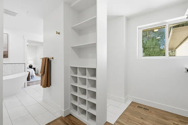 Built-in shelving and cubby storage, a freestanding soaking tub with tile surround, and large window with natural light
