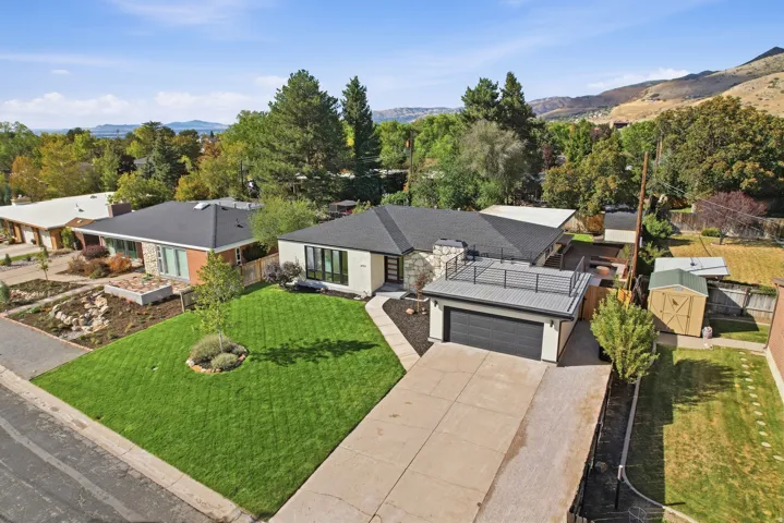 Contemporary exterior with a flat roofline, attached garage with a dark door, concrete driveway, and a front lawn