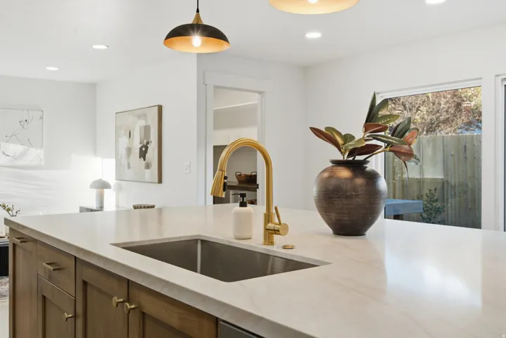 Kitchen island with an undermount sink, brass-finish faucet, recessed lighting, and a pendant light fixture