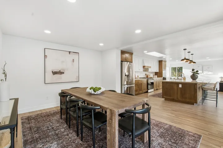 Recessed lighting, wood-finish flooring, two-tone kitchen cabinetry, stainless steel appliances, and a kitchen island with seating