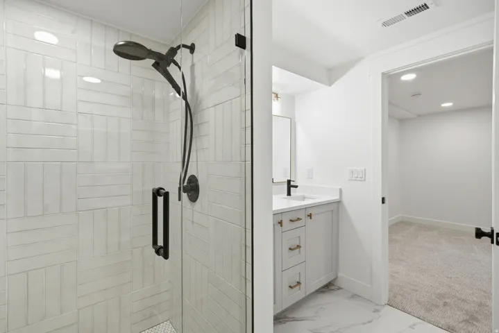Glass-enclosed shower with a matte black shower system and textured subway tile surround
