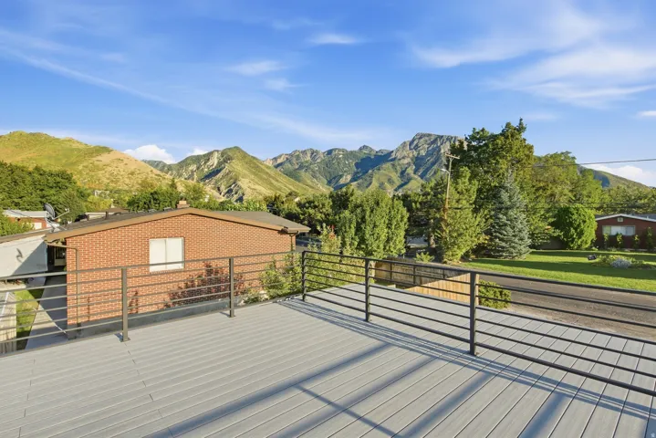 Spacious outdoor deck featuring composite decking and black metal railings, set against a mountain backdrop