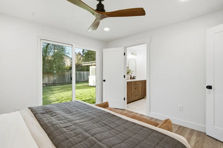 Hardwood-style flooring, white walls, and a contemporary ceiling fan with wood-finish blades