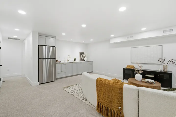 Integrated wet bar with gray shaker cabinetry, undermount sink, and stainless steel refrigerator