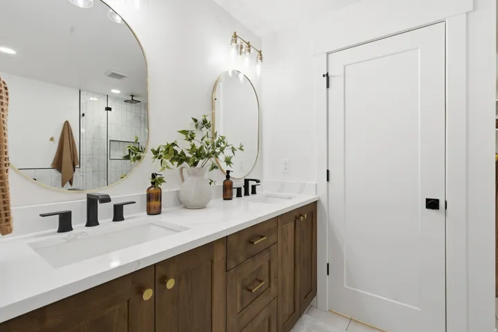 Dual vanity with white countertop, dark wood-finish cabinetry, and matte black fixtures