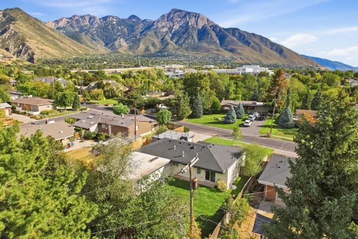 Expansive mountain backdrop, residential neighborhood setting, mature trees, manicured lawns, asphalt roadways