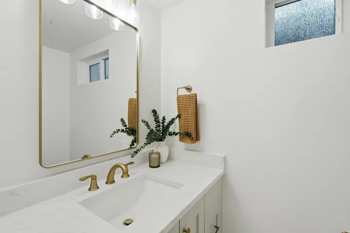 White vanity with integrated sink, brass-finish faucet, and coordinating hardware
