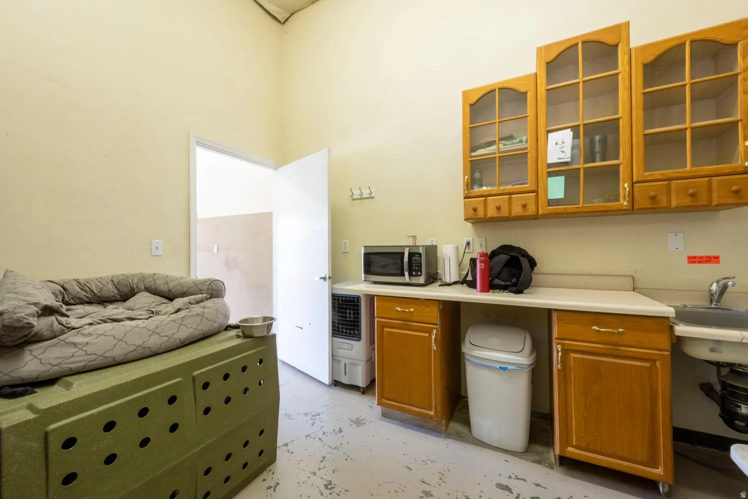 Functional utility space with overhead cabinetry featuring glass panel doors, solid wood base cabinetry, and a built-in sink