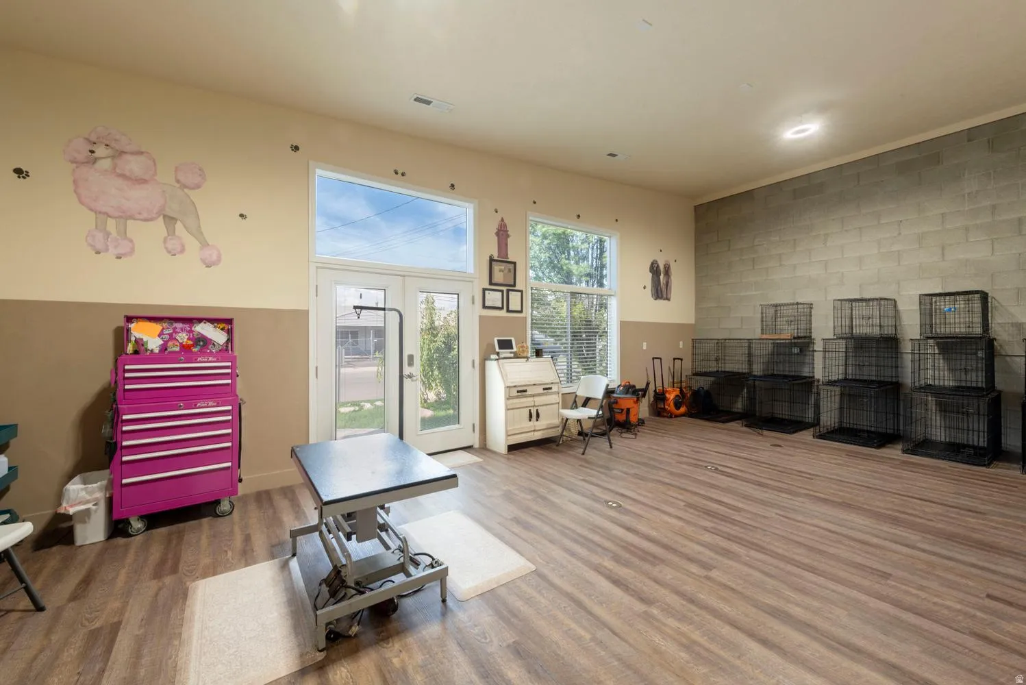 Wood-finish flooring, high ceilings, large windows providing natural light, glass-paned double doors, and a block-finish accent wall