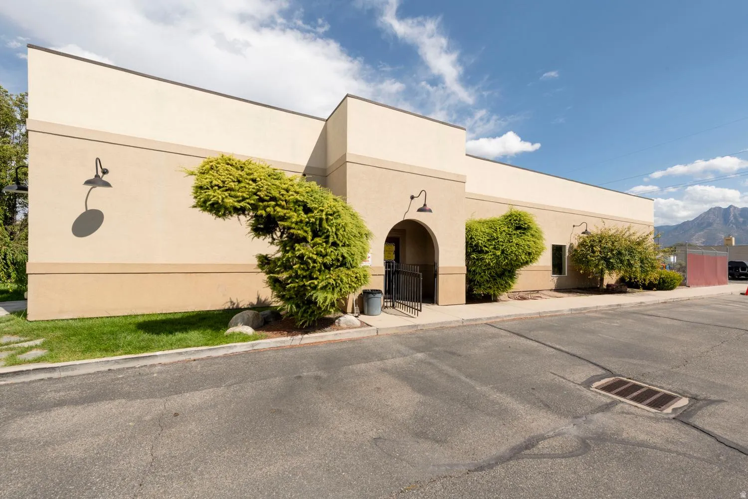 Stucco exterior with multiple wall-mounted light fixtures and an arched entry