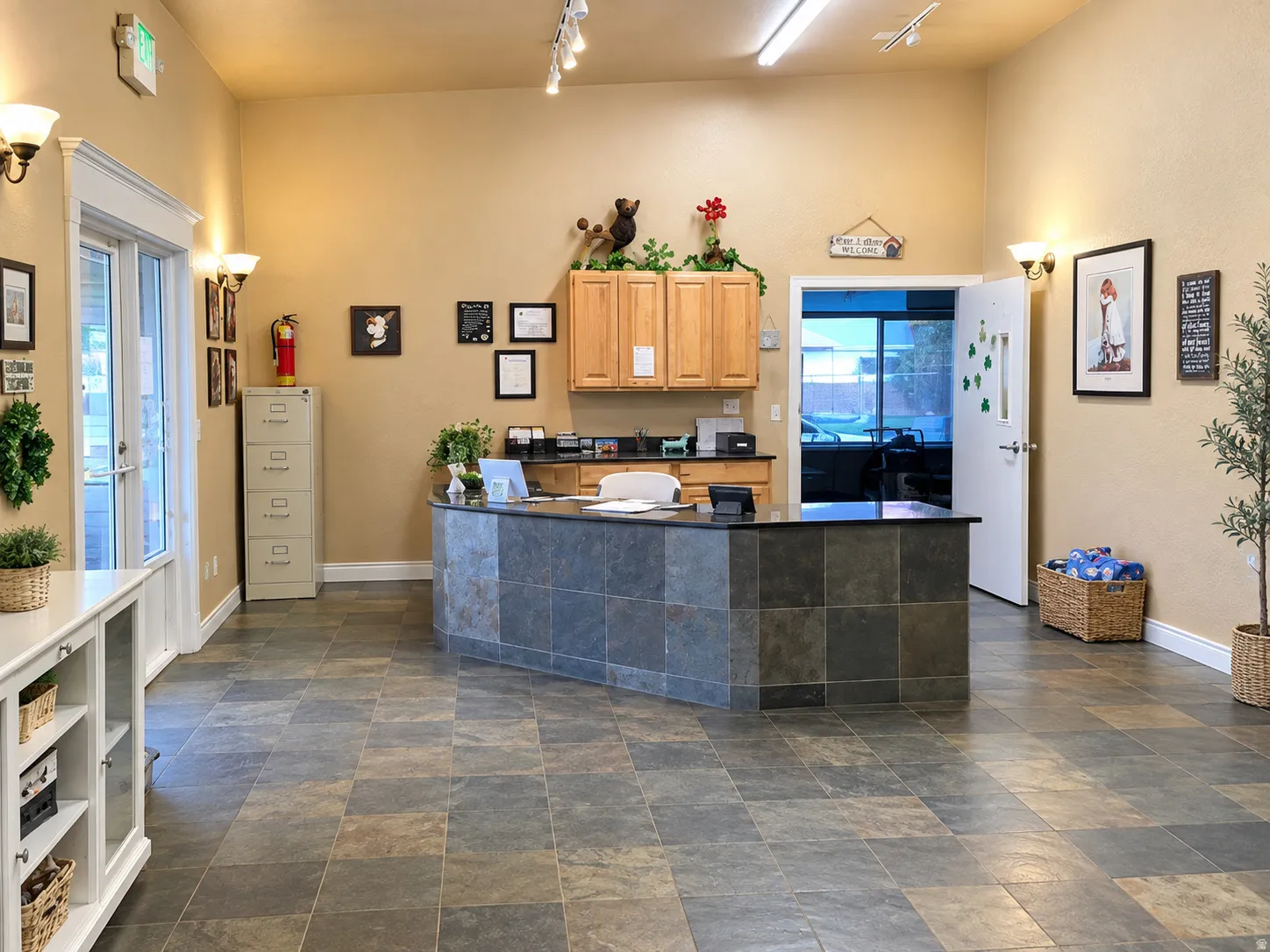 Tiled flooring throughout, curved reception desk with a dark countertop, upper wood-finish cabinetry, recessed lighting, and wall sconces