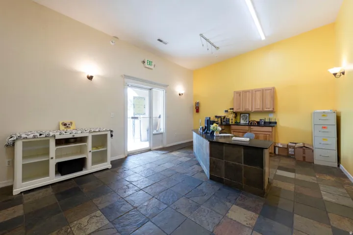 Spacious room featuring stone tile flooring, a built-in reception desk with a stone facade, wood cabinetry, and a sliding glass door