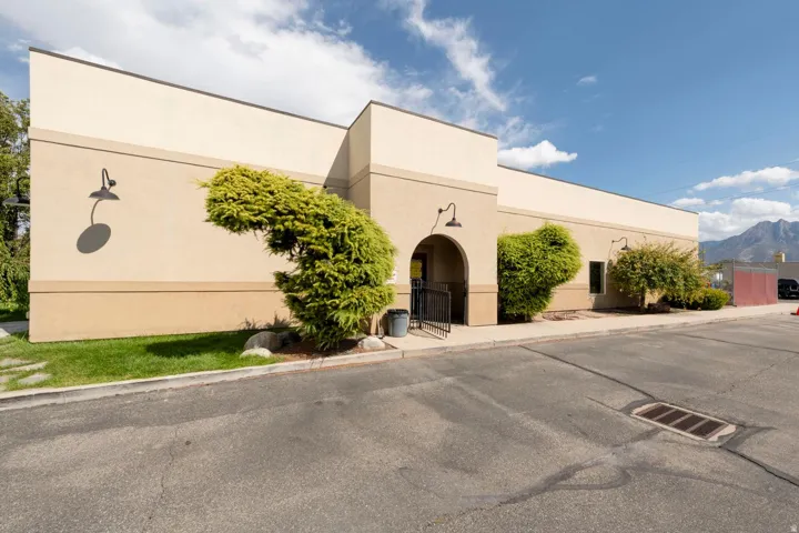 Stucco exterior with multiple wall-mounted light fixtures and an arched entry