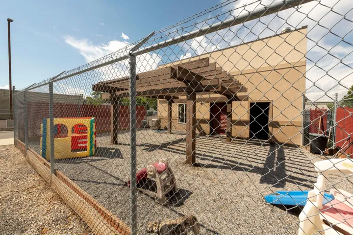 Enclosed outdoor area featuring a wood pergola and chain-link fencing