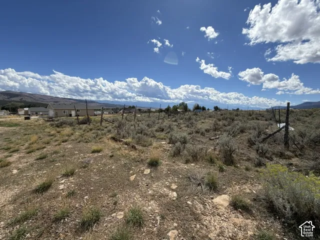 Expansive land parcel featuring natural shrubbery and distant mountain formations