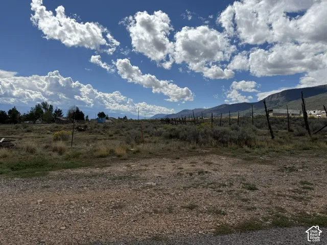 Expansive land parcel featuring natural shrubbery and distant mountain formations