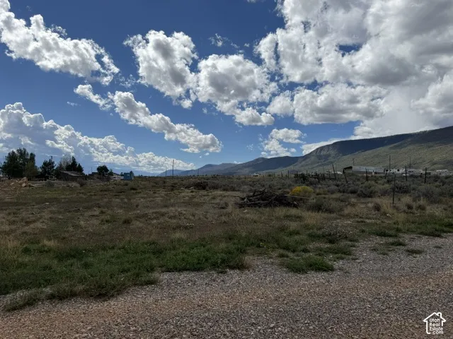 Expansive undeveloped lot with natural ground cover and distant mountainous terrain