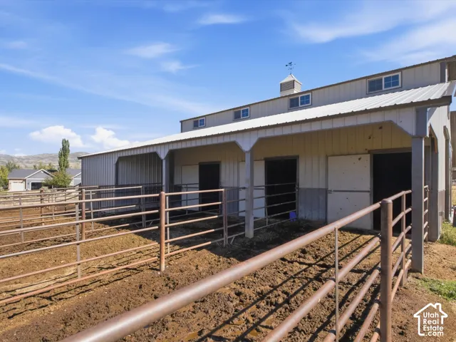 Barn structure with a metal roof, cupola, multiple windows, and integrated stalls