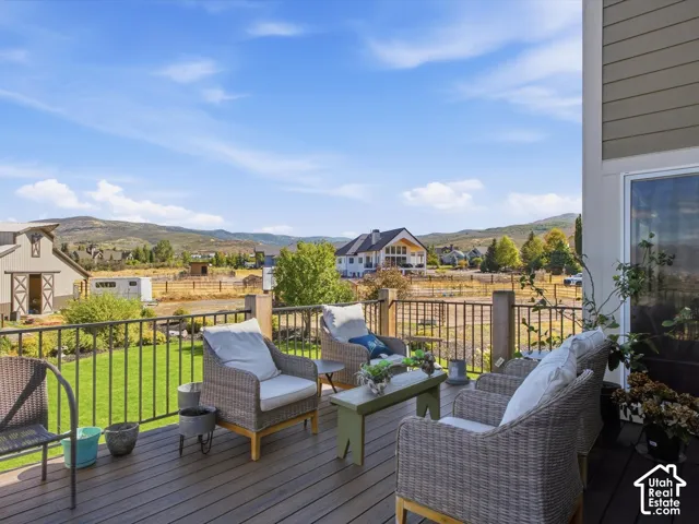 Expansive outdoor deck with composite decking and metal railings, featuring a verdant lawn and distant mountain scenery