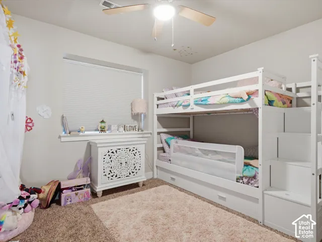 Ceiling fan with integrated lighting, window with blinds, decorative console table, bunk bed with built-in storage steps, and wall-to-wall carpeting