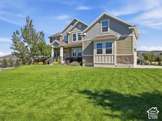 Two-story residence featuring composite siding, stone veneer accents, multiple gable roofs, and a front porch with columns
