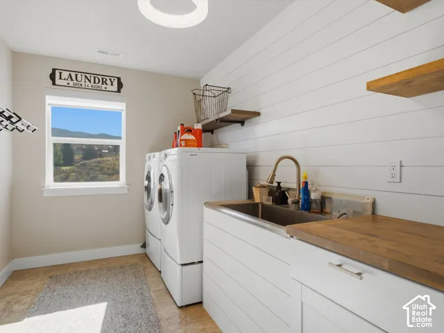 White shiplap accent wall, wood-finish open shelving, and a built-in utility sink with a wood-finish countertop
