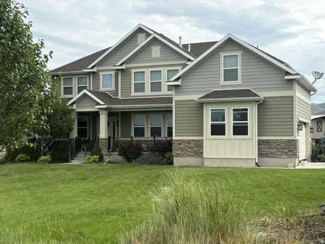 Multi-level residence featuring a prominent bay window, stone veneer accents, and a covered porch with column supports
