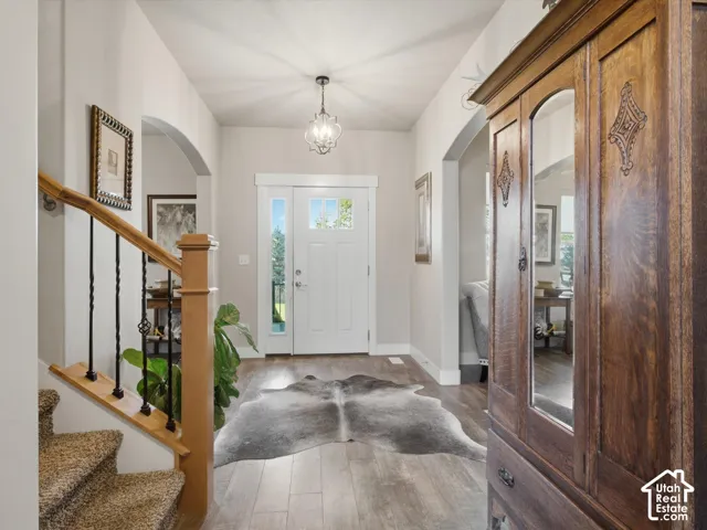 Entryway featuring wood-finish flooring, a decorative overhead light fixture, and arched doorways