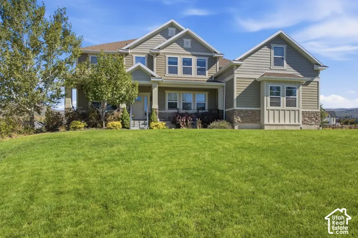 Expansive lawn, two-story residence, horizontal siding, stone veneer accents, covered porch