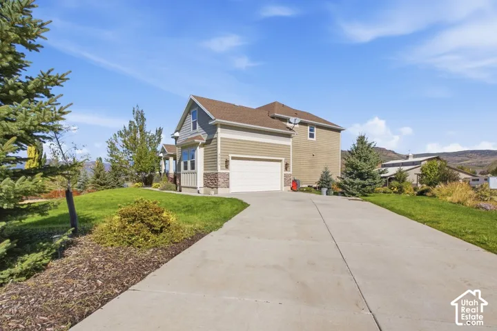 Two-story residence featuring siding and stone exterior accents, an attached garage, and a concrete driveway