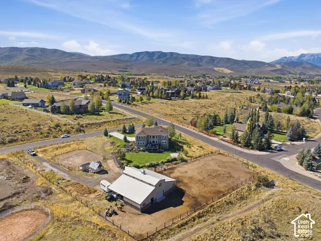 Expansive property featuring a large barn structure, multiple fenced enclosures, and a traditional-style residence with a manicured lawn