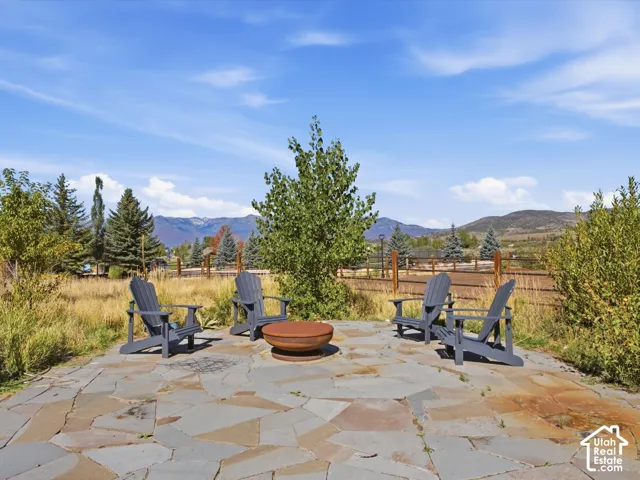 Outdoor patio featuring flagstone paving, a central fire pit, and expansive mountain scenery