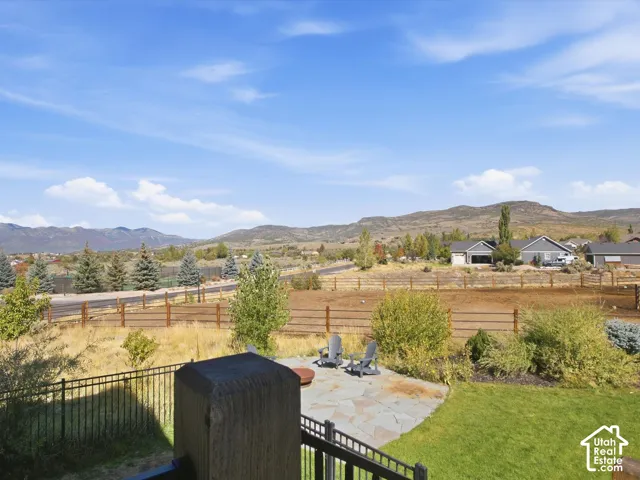 Expansive patio with stone pavers, green lawn, and mountain scenery