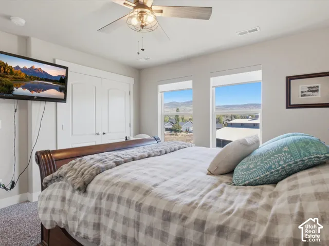 Recessed double-door built-in cabinetry, wood-finish bed frame, and ceiling fan with integrated lighting