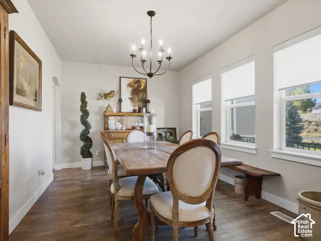 Wood-finish flooring, multiple windows, archway entry, and a chandelier lighting fixture