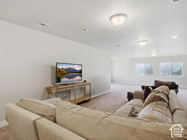 Recessed and flush mount ceiling lighting, light neutral wall paint, textured carpet flooring, window blinds, and multiple windows